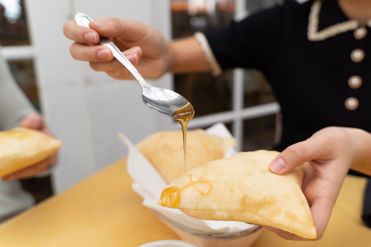 A customer drizzles honey onto the corner of a sopaipilla.
