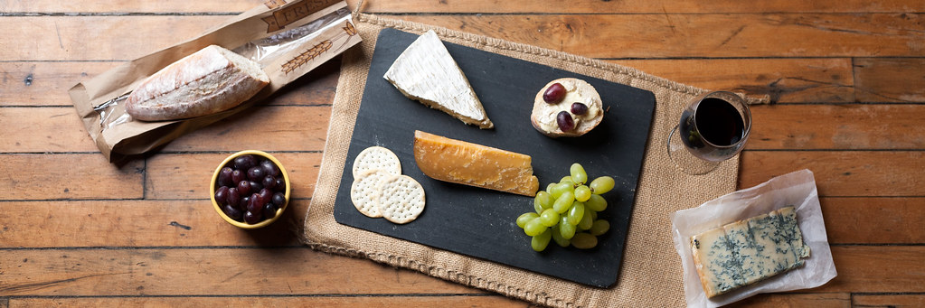 Dark slate board with sliced cheeses and crackers