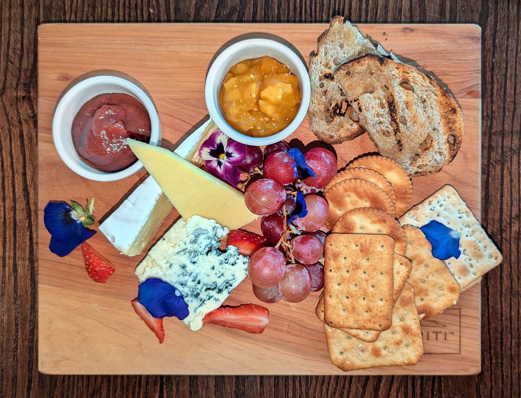 A cheese and charcuterie board with grapes and crackers